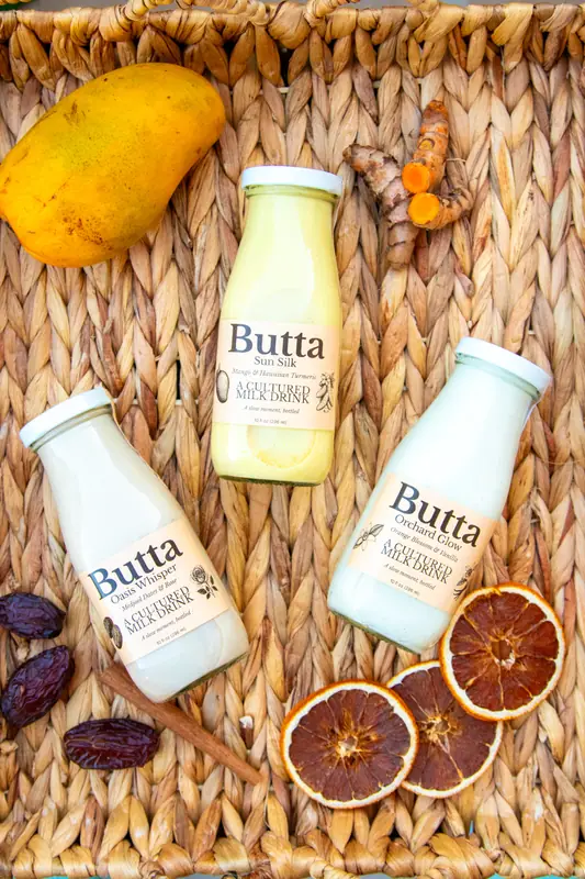 Four Butta bottles on a woven tray with fruit and spices