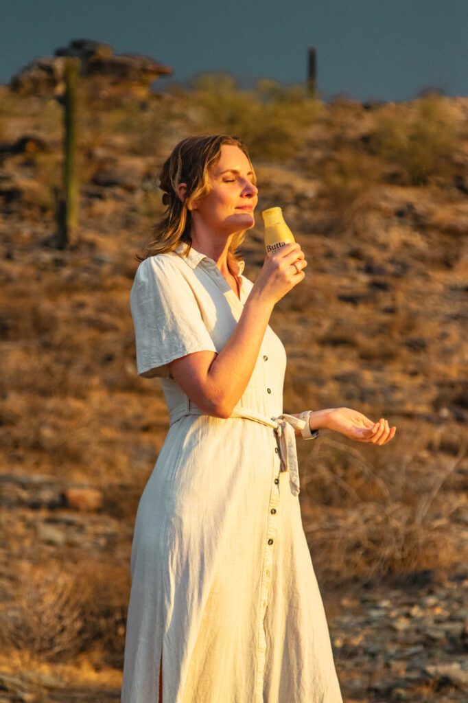 woman drinking Butta cultured milk drink in the desert at sunset
