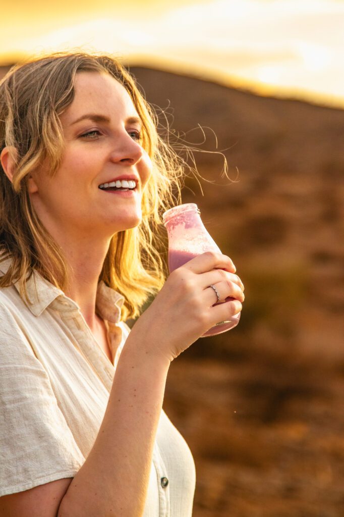 Woman enjoying Butta Crimson Sunset cultured milk drink in warm desert light