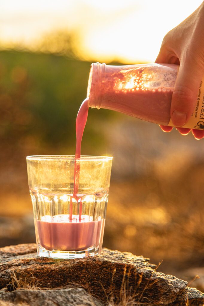 Pouring Butta cultured milk drink into a glass in the Arizona desert at sunset